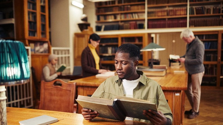 Hombre leyendo en una biblioteca