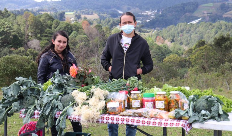 Dos personas mostrando productos agrícolas
